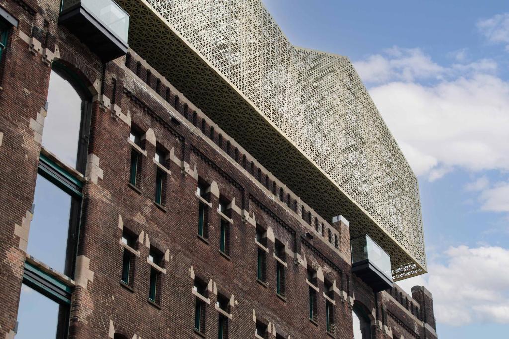 Historic brick façade of Brede Hilledijk 95 with its contemporary gold extension, Rotterdam