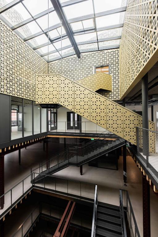 Light-filled atrium with gold panelling and steel staircases at Brede Hilledijk 95